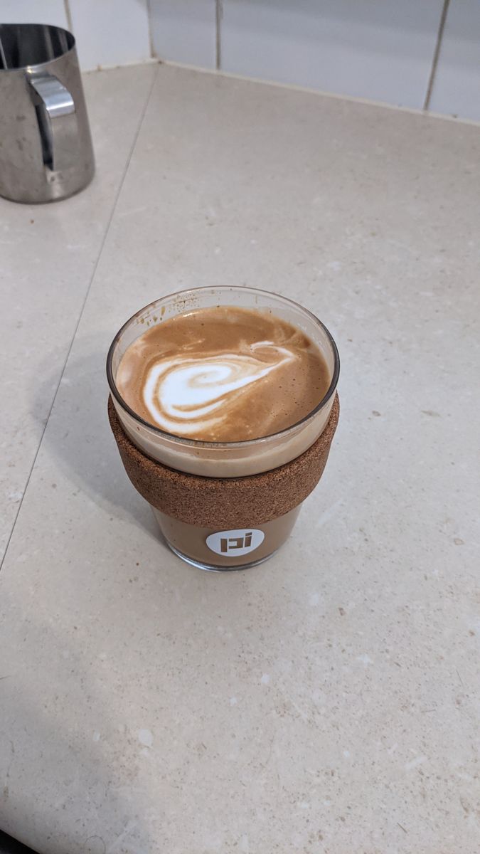 Cork travel cup with a white swirl of milk on the coffee