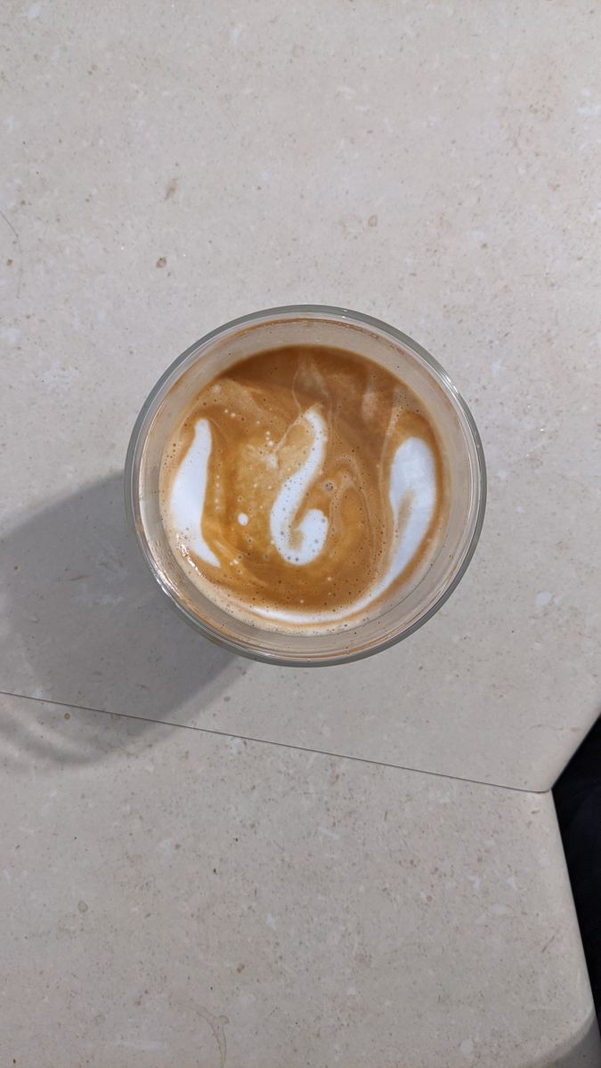 Glass of coffee from above with a white swan-like shape in the milk