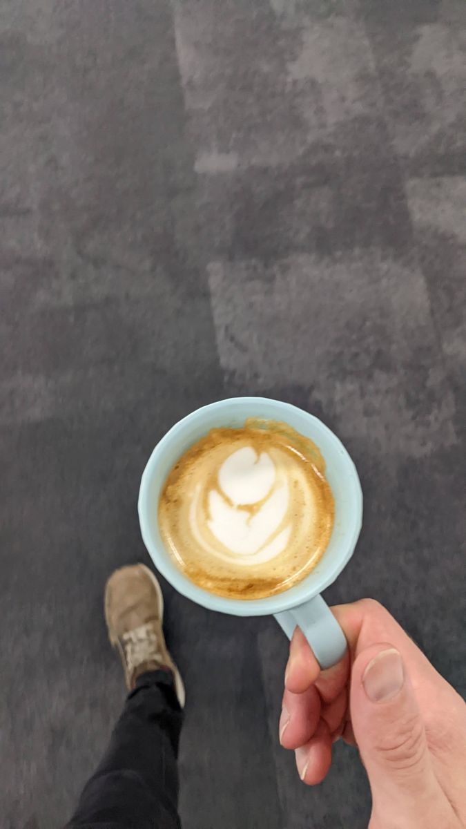 Pale blue mug held over a carpet, with a loose rosetta pattern in the foam