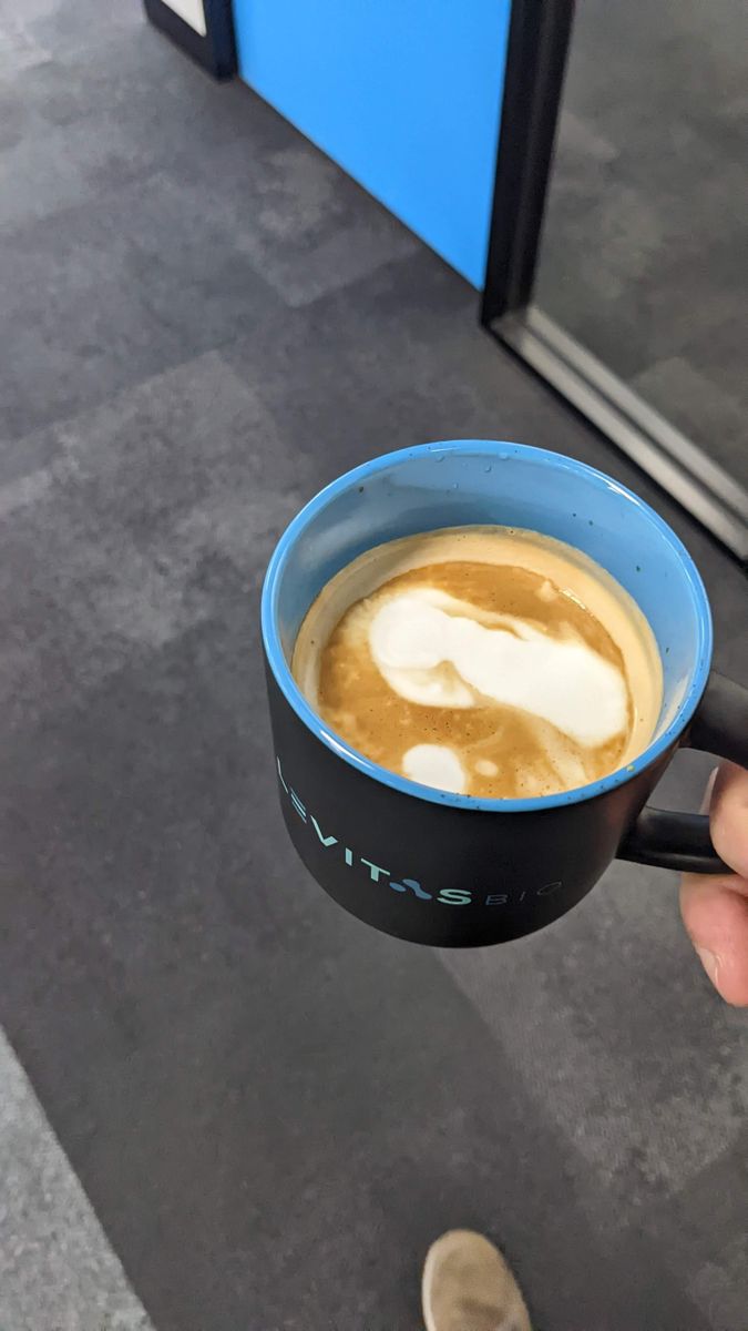 Blue mug held over a carpet, with a single white cloud-shaped blob of milk